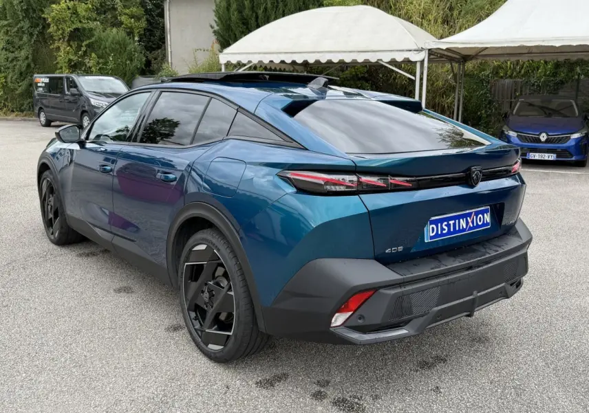Vue 3/4 arrière droite d'une Peugeot 408 PHEV 225 GT bleu avec feux arrière LED et jantes noires distinctives.