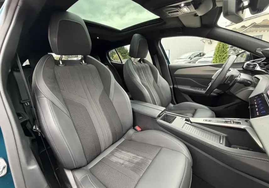 Vue intérieure avant droite du Peugeot 408 PHEV 225 GT 2023 bleu, sièges cuir et alcantara noirs avec toit panoramique.