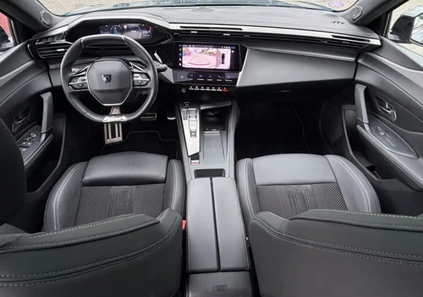Vue intérieure avant du Peugeot 408 PHEV 225 GT 2023, tableau de bord noir avec écran tactile affichant caméra de recul.