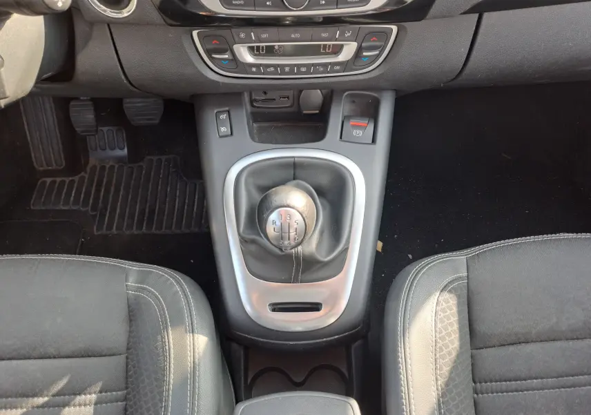 Vue plongeante sur la console centrale du Renault Scenic III gris, mettant en valeur le levier de vitesse manuel et les sièges noirs.