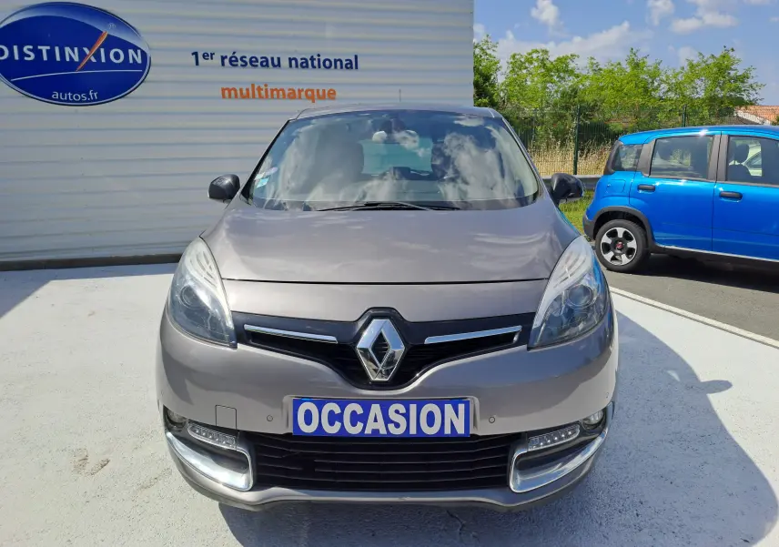 Vue de face d'une Renault Scenic III gris métallisé avec plaque "OCCASION" sur un parking extérieur.