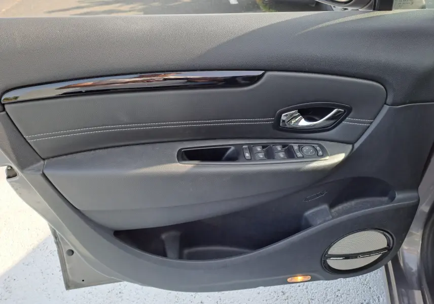 Porte avant gauche intérieure gris foncé du Renault Scénic III 2016 avec commandes de vitres et haut-parleur Pioneer.