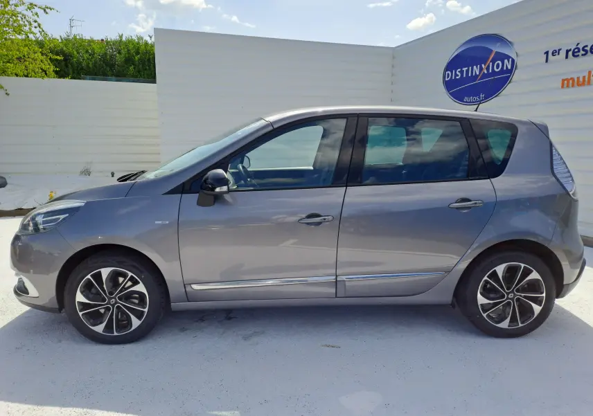 Profil côté gauche d’un Renault Scénic III gris 2016 avec jantes alliage et vitres teintées sur fond clair.