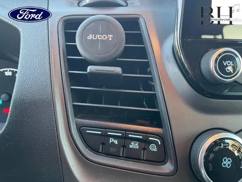 Gros plan sur la console centrale du Ford Transit Custom gris, montrant les aérations et commandes du système audio.