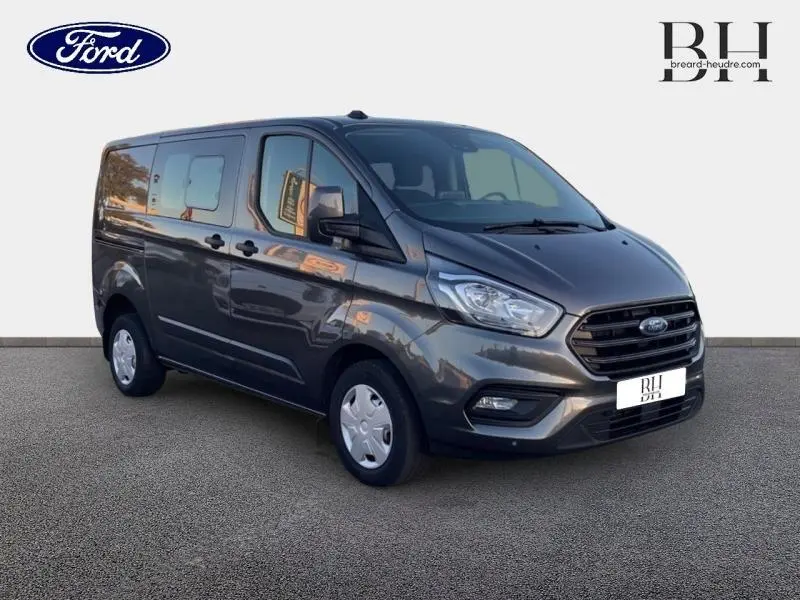 Ford Transit Custom Fourgon gris métallisé vu en 3/4 avant droit, avec double portes latérales et calandre noire distinctive.