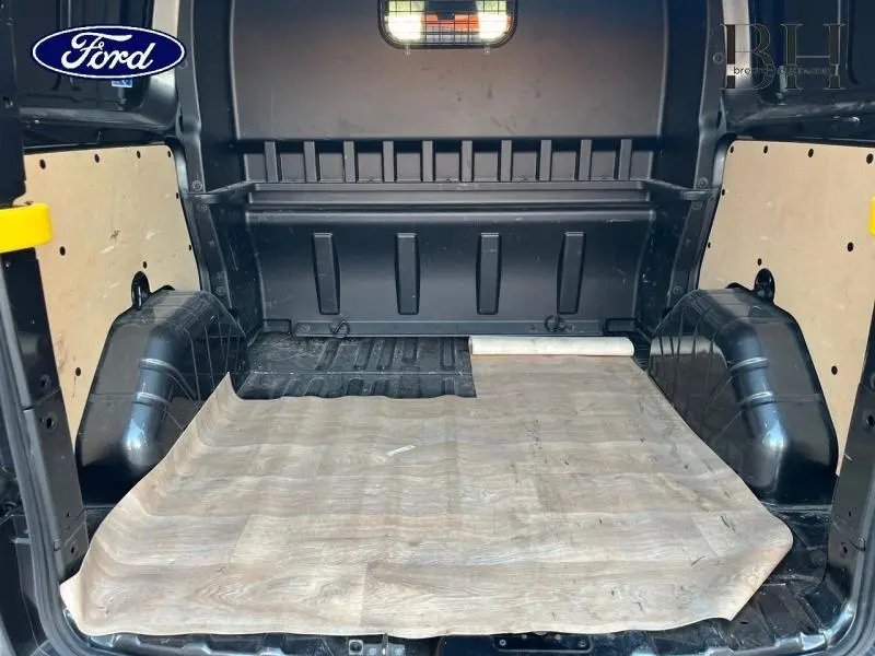 Vue intérieure arrière du fourgon Ford Transit Custom gris, montrant l'espace de chargement avec revêtement au sol en bois clair.