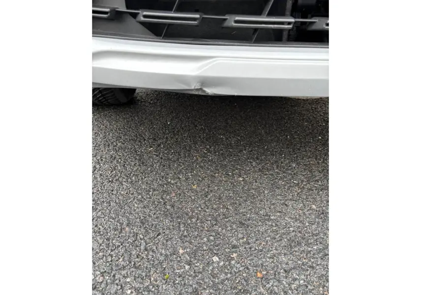 Gros plan sur le pare-chocs avant blanc du Renault Captur 2024, avec une bosse visible au centre.