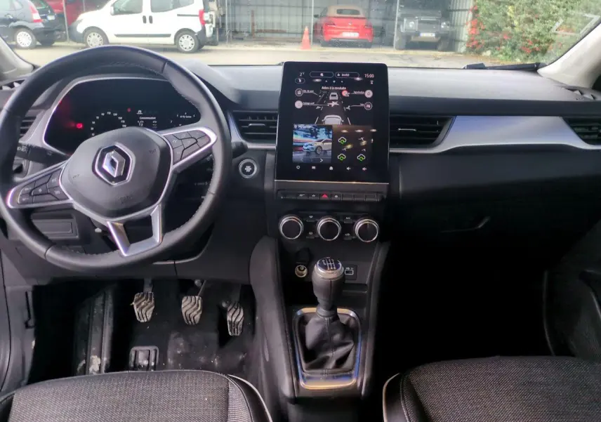 Vue intérieure avant du Renault Captur 2024 montrant le volant, la boîte manuelle et l'écran tactile central noir.