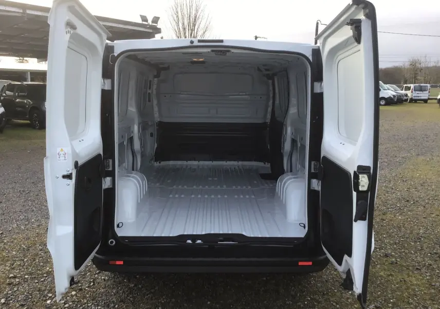 Vue arrière du Renault Trafic Fourgon blanc 2025 avec portes ouvertes montrant l'espace de chargement vide et la cloison intérieure.