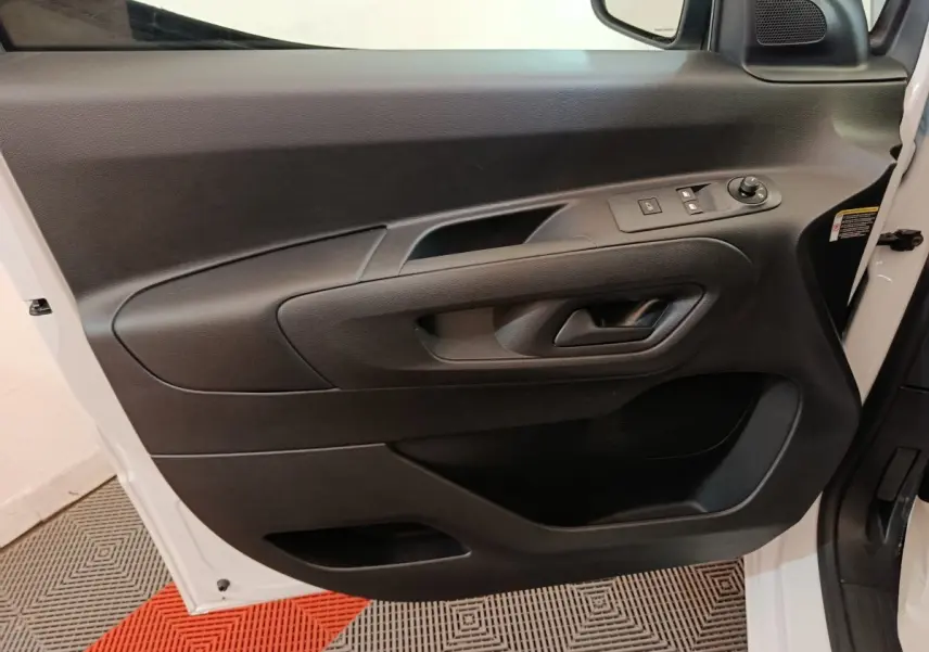 Vue rapprochée de la porte avant gauche blanche du Peugeot Partner 2025 avec commandes électriques et poignée noire intégrée.