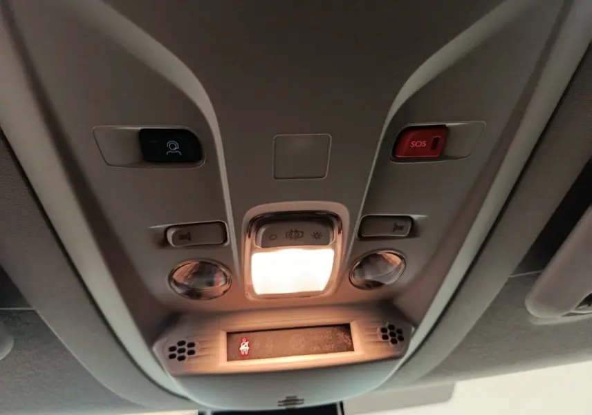 Vue intérieure du plafonnier du Peugeot Partner blanc 2025 avec boutons SOS et éclairage central allumé.