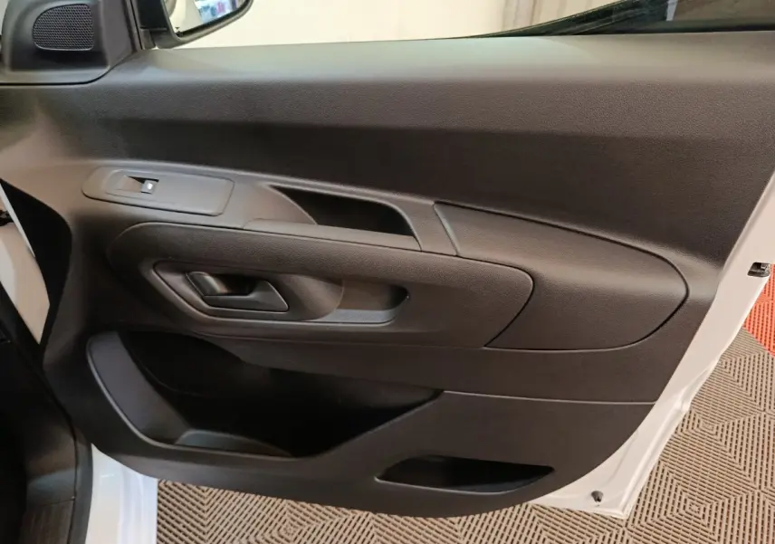 Vue rapprochée de la porte avant droite noire du Peugeot Partner blanc 2025, avec poignée et commande de vitre.