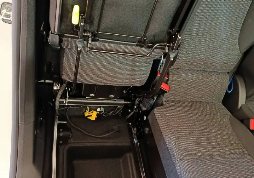 Vue intérieure en plongée du siège passager relevé du Peugeot Partner blanc, montrant la structure métallique et le rangement sous siège.