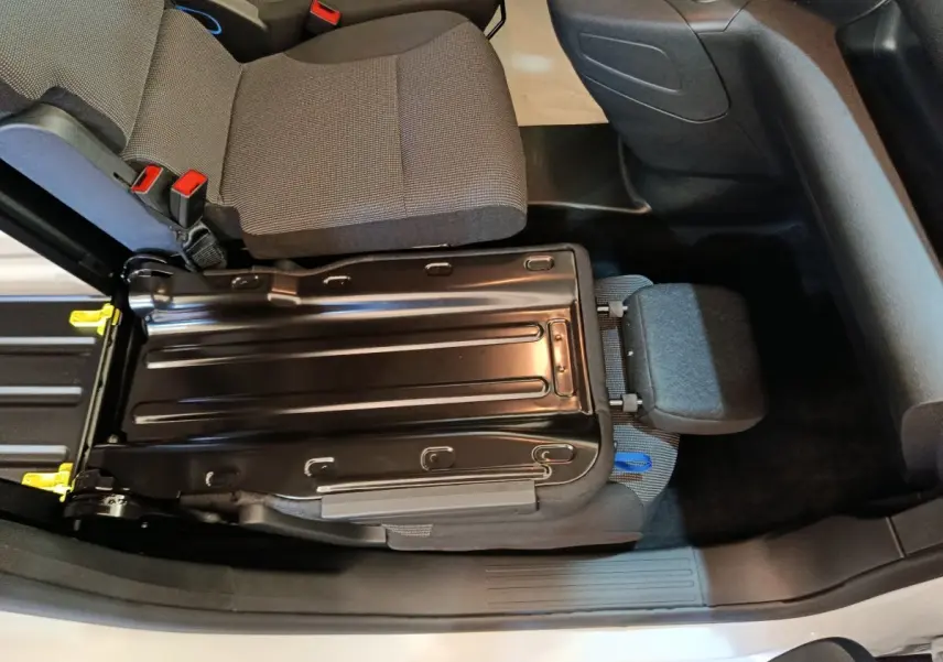 Vue intérieure du siège passager avant relevé du Peugeot Partner blanc, montrant la structure métallique et l'assise grise.