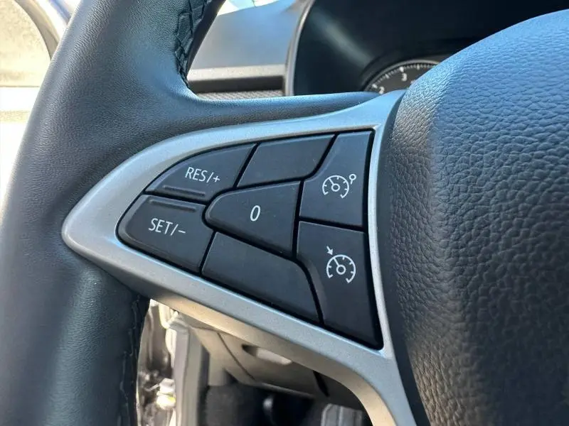 Gros plan sur les commandes de régulateur de vitesse au volant du Dacia Jogger 2025, cuir noir et insert gris.