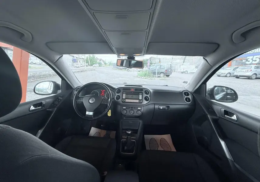 Vue intérieure avant du Volkswagen Tiguan 2007, tableau de bord et volant noirs avec boîte manuelle visible.