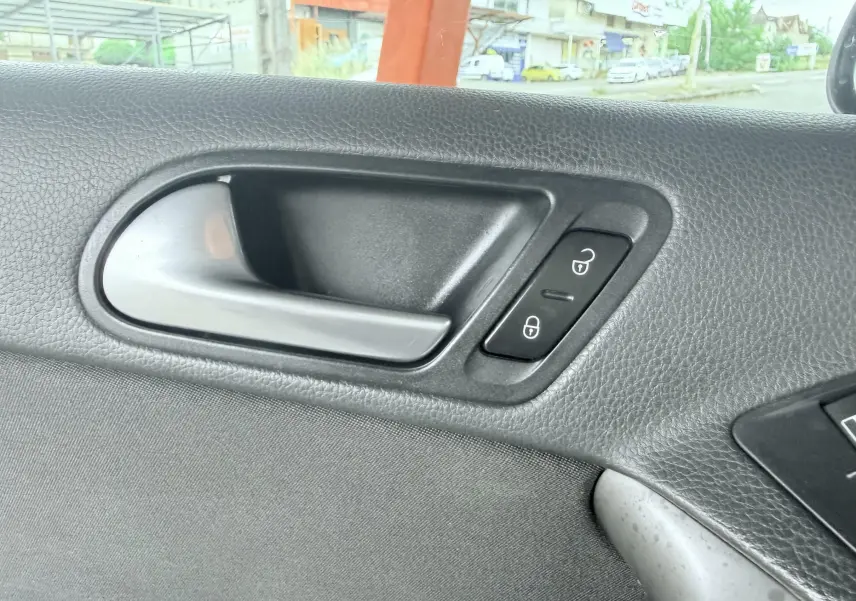 Poignée intérieure de porte côté gauche du Volkswagen Tiguan noir, avec boutons de verrouillage visibles.