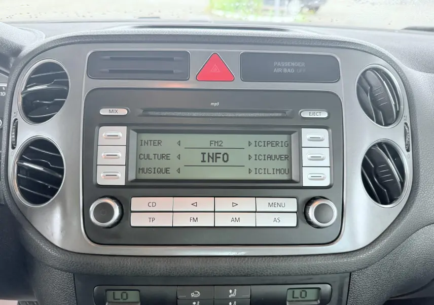 Vue rapprochée du tableau de bord noir du Volkswagen Tiguan 2007, mettant en valeur l'autoradio et les aérateurs circulaires.