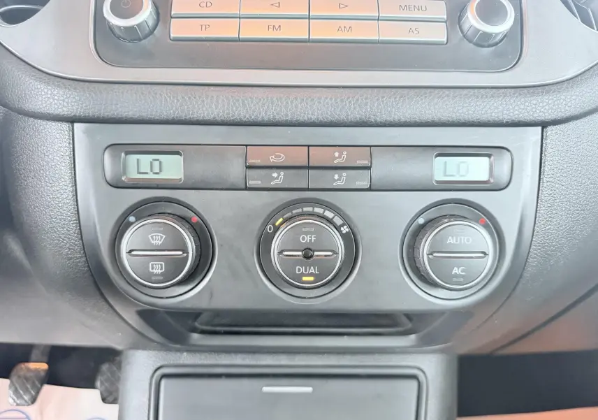 Vue rapprochée de la console centrale du Volkswagen Tiguan 2007, montrant les commandes de climatisation automatique et radio.