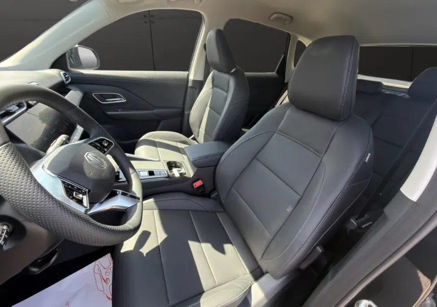 Vue intérieure côté conducteur du MG ZS noir 2026, sièges en cuir noir et volant multifonctions avec logo MG visible.