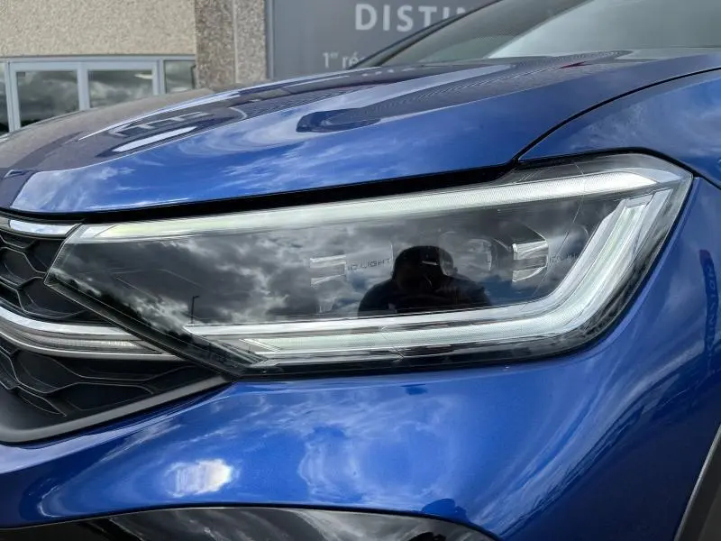 Gros plan sur le phare avant droit LED du Volkswagen Taigo 1.5 TSI R-Line bleu récif métallisé avec calandre noire.