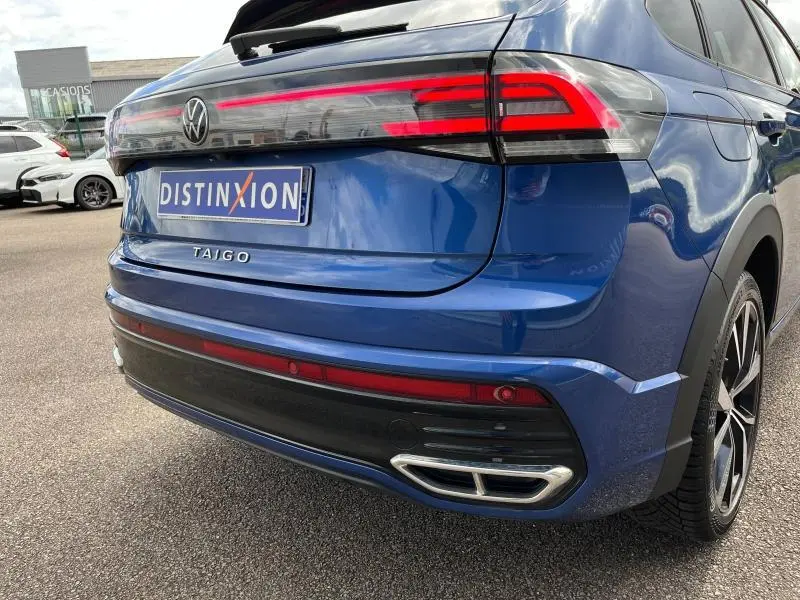 Vue 3/4 arrière droite du Volkswagen Taigo bleu récif métallisé avec feux arrière LED et double sortie d'échappement chromée.