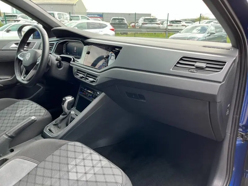 Vue intérieure côté passager du Volkswagen Taigo R-Line 2023 avec sellerie tissu R-Line gris et tableau de bord moderne noir.