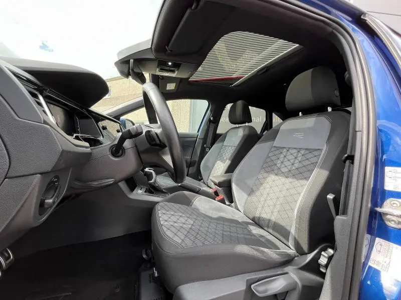 Intérieur avant du Volkswagen Taigo bleu récif, sièges sport R-Line en tissu gris avec toit ouvrant panoramique en verre.