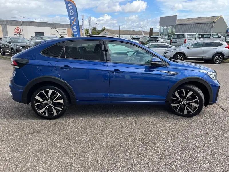 Profil côté gauche d'un Volkswagen Taigo 1.5 TSI R-Line bleu récif métallisé avec jantes alliage et vitres surteintées.