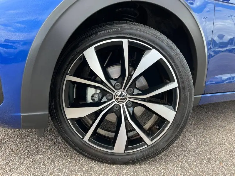 Gros plan sur la jante alliage noire et argent du côté avant droit du Volkswagen Taigo bleu récif métallisé.