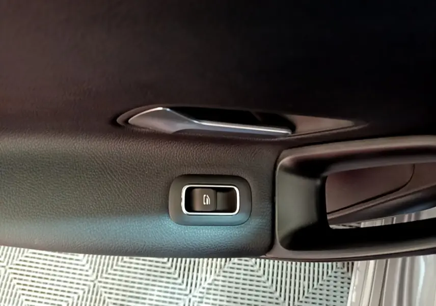 Gros plan sur la poignée intérieure et le bouton de verrouillage de la porte côté conducteur d'une Mercedes Classe A gris foncé.