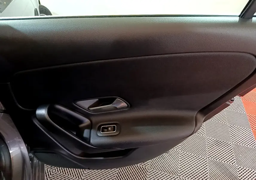 Intérieur de la porte côté gauche d’une Mercedes Classe A 180 d Business Line gris foncé, avec poignée et bouton de vitre électrique.