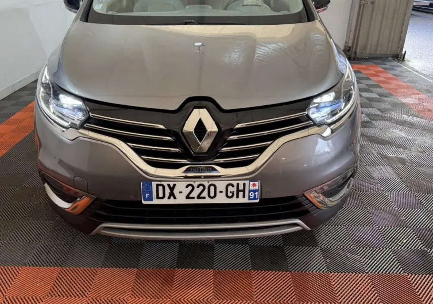 Vue avant d’un Renault Espace Initiale Paris gris foncé avec phares LED allumés et calandre chromée visible.