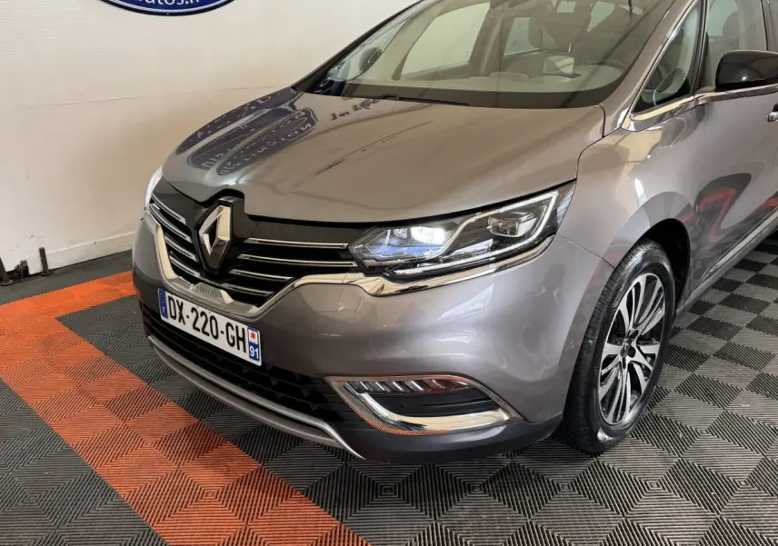 Vue 3/4 avant droit d’un Renault Espace gris foncé avec phares LED et calandre chromée dans un showroom.
