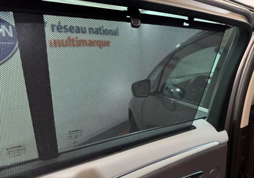 Vue intérieure côté gauche de la porte arrière du Renault Espace gris foncé avec store pare-soleil manuel visible.