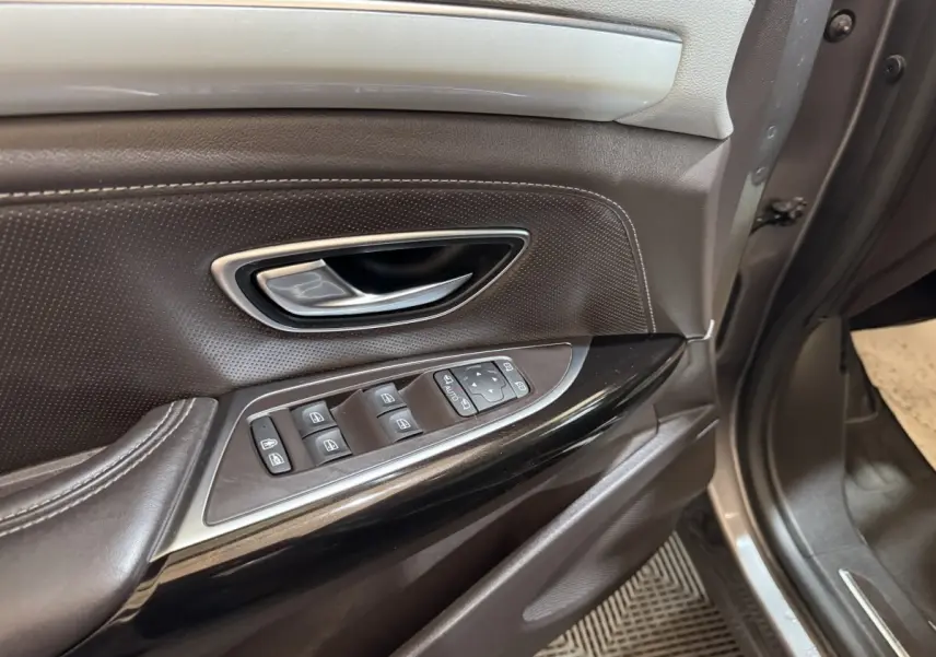 Gros plan sur la porte avant gauche gris foncé de Renault Espace 2015 avec commandes électriques des vitres et poignée chrome.