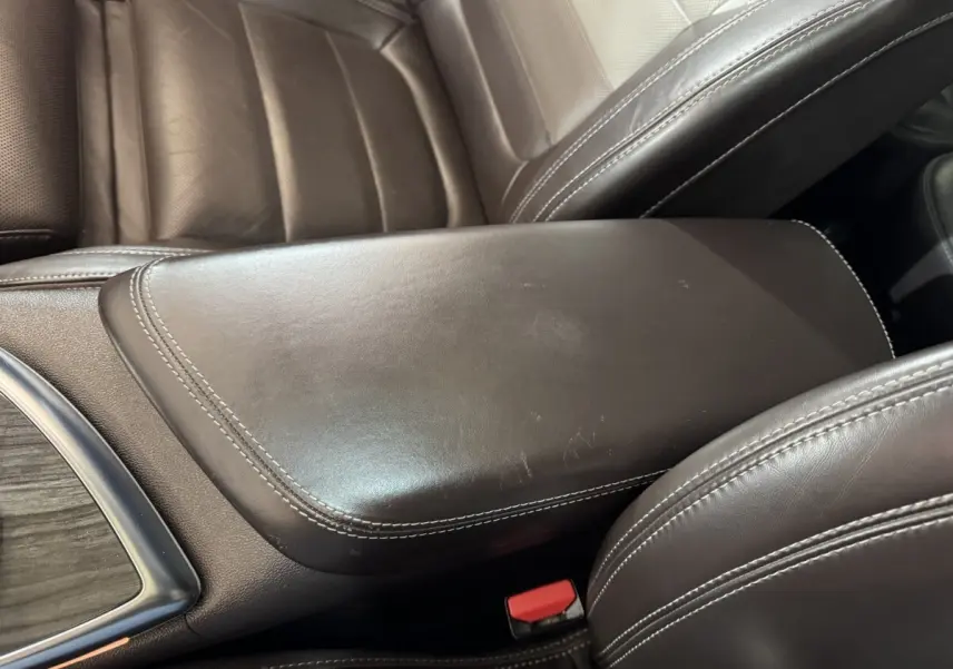 Détail de l'accoudoir central en cuir marron avec surpiqûres blanches dans l'habitacle du Renault Espace gris foncé 2015.