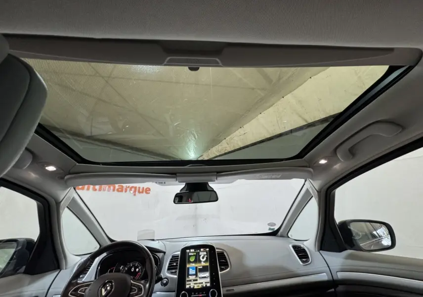 Vue intérieure avant du Renault Espace gris foncé 2015, avec grand toit panoramique et écran tactile central vertical.