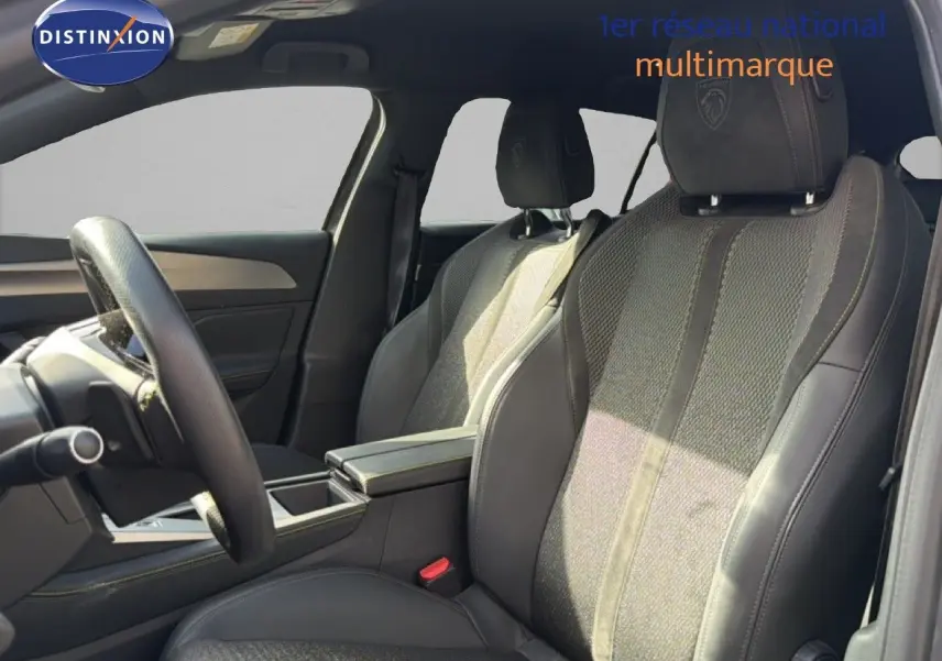 Vue intérieure côté gauche du Peugeot 408 1.2 HYBRID 145CH GT, sièges en tissu gris et cuir avec logo Peugeot brodé.