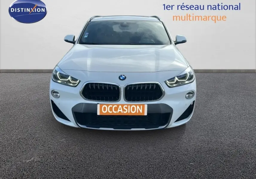 Vue avant d'un BMW X2 blanc avec calandre noire et phares LED allumés sur fond neutre.