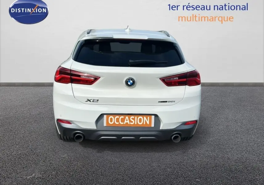 Vue arrière d’un BMW X2 blanc F39 sDrive 20i 2018 avec double sortie d’échappement et feux rouges distinctifs.
