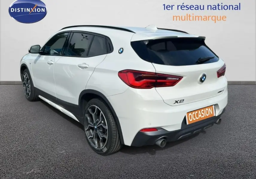 BMW X2 blanc vue 3/4 arrière droit, jantes alliage 19 pouces et toit ouvrant panoramique visibles.