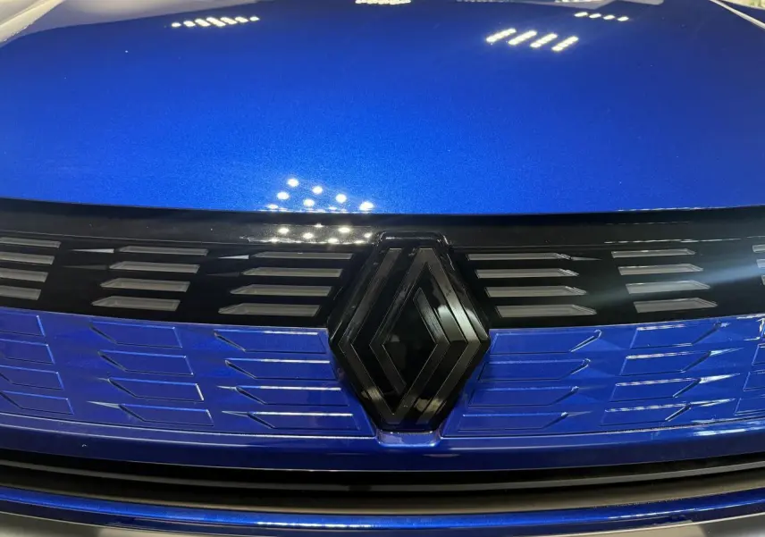 Gros plan sur la calandre avant bleu métallisé du Renault Symbioz avec logo noir brillant au centre.