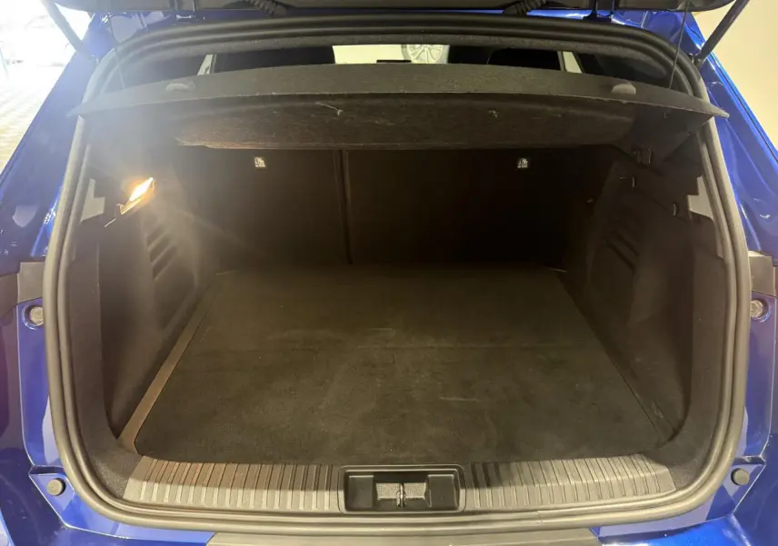 Coffre ouvert vu de l'arrière d'une Renault Symbioz bleu, montrant un espace de chargement spacieux et éclairé.