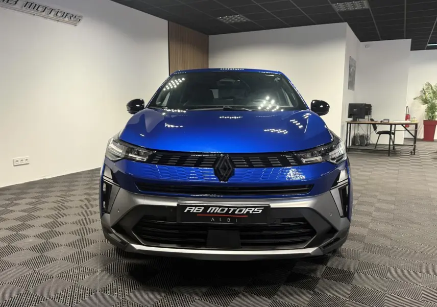 Vue de face d'une Renault SYMBIOZ 1.6 E-Tech Hybride bleu Iron avec calandre noire et détails gris mat en showroom.