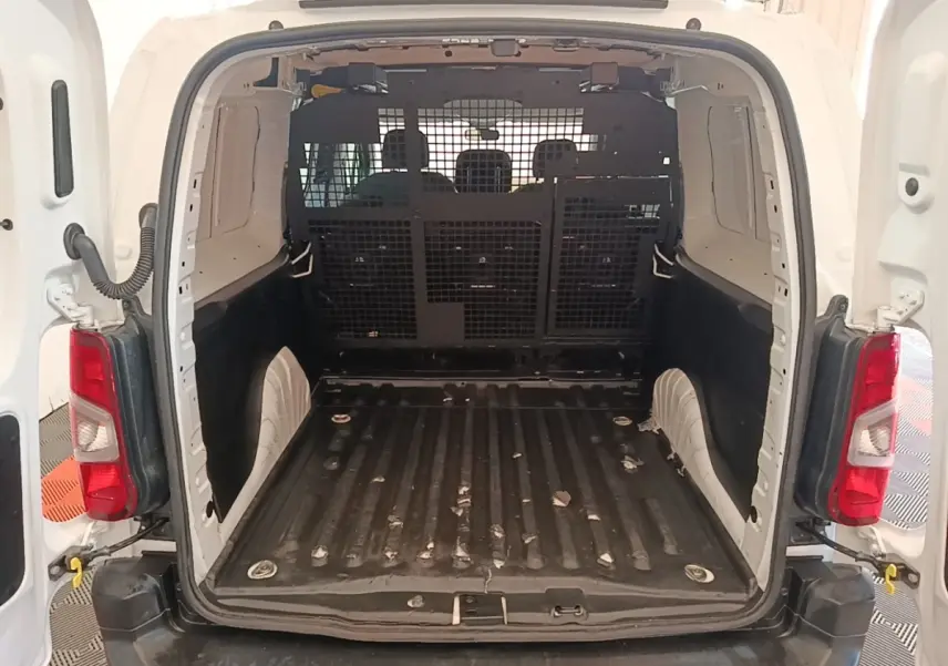 Vue arrière du Peugeot Partner blanc 2020, montrant l’espace de chargement vide avec cloison grillagée pleine.