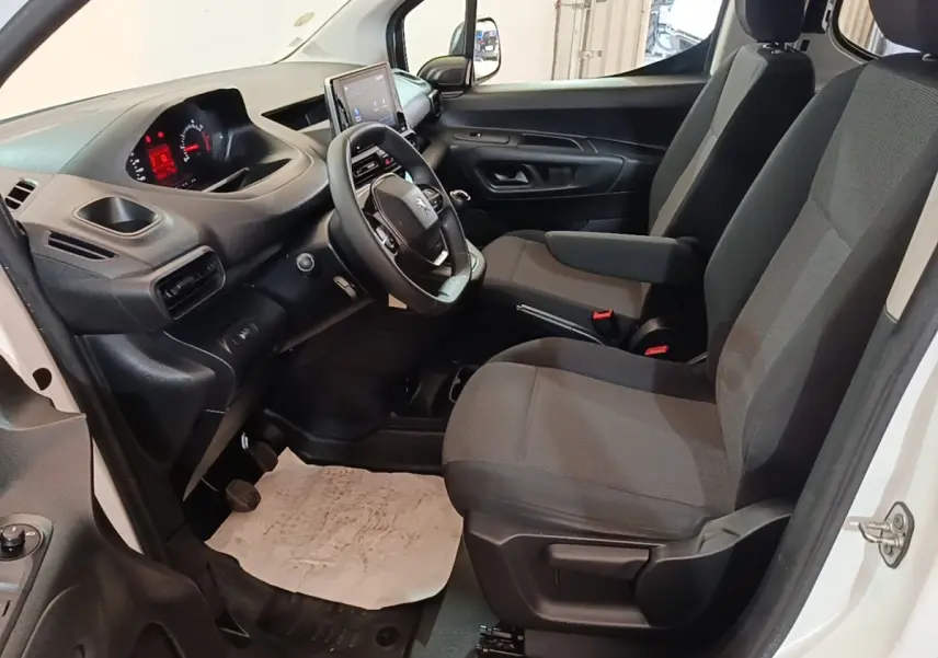 Vue intérieure côté conducteur du Peugeot Partner blanc 2020, montrant le tableau de bord et les sièges avant gris.