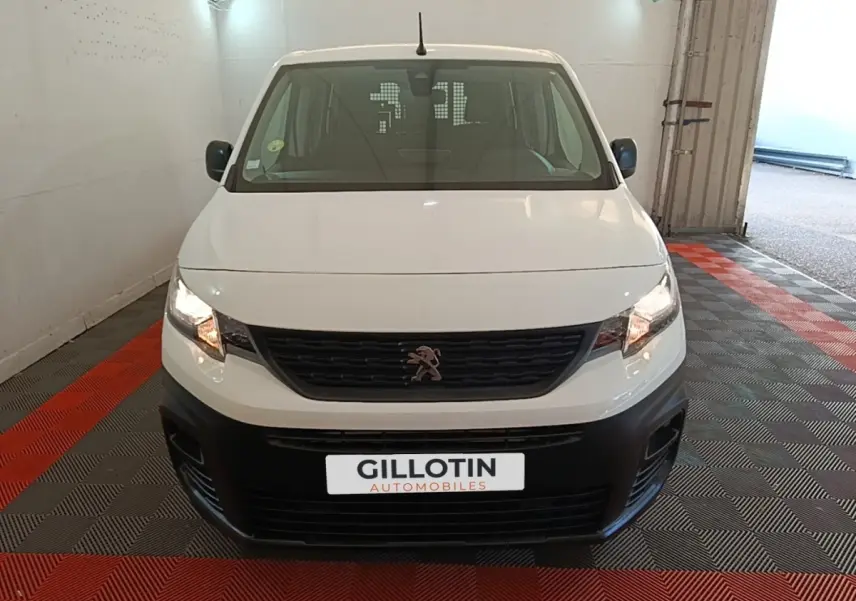 Vue avant d'un Peugeot Partner blanc avec calandre noire et pare-chocs noir dans un garage fermé.
