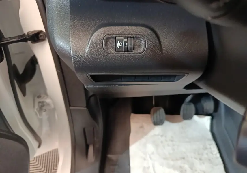 Vue intérieure côté conducteur du Peugeot Partner blanc 2020, montrant les pédales et le réglage des phares.