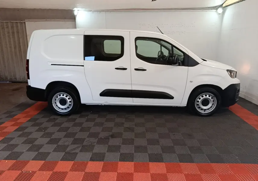 Vue de profil côté gauche d'un Peugeot Partner blanc, utilitaire avec vitres avant et arrière et jantes acier.